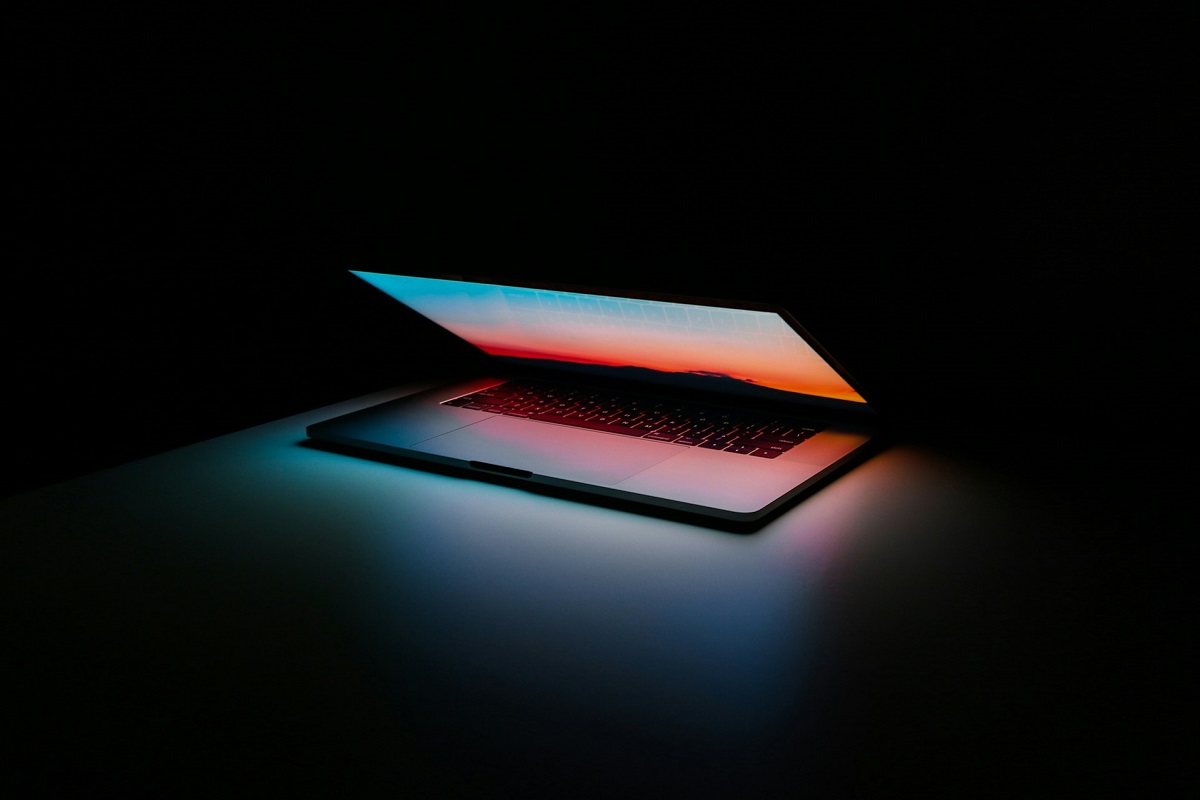 half open laptop with a glowing screen in a dark room