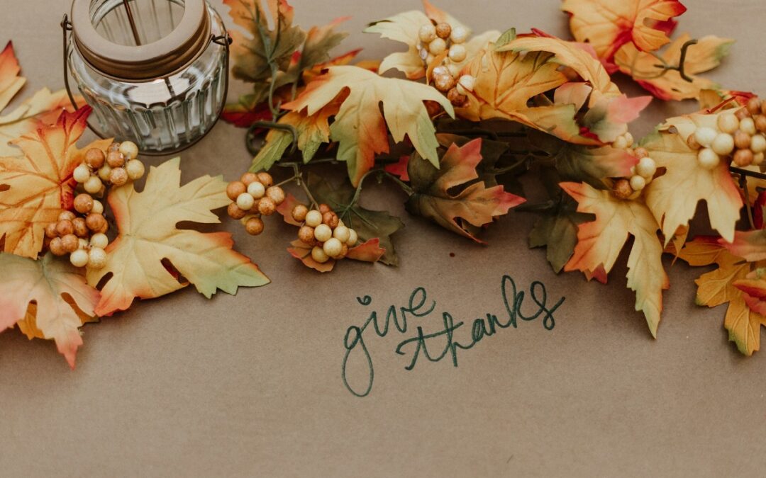 Autumn leaves on a table with the words give thanks written next to them