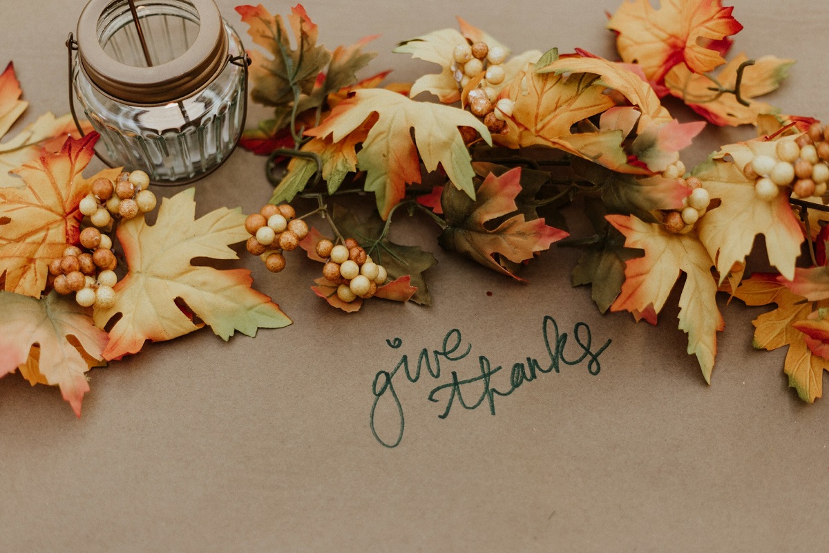 Autumn leaves on a table with the words give thanks written next to them